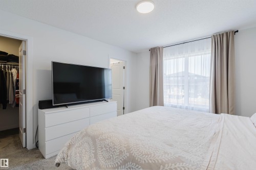 Bright sleeping area featuring light gray carpeting and a large window with sheer and blackout curtains - 5237 Edgemont Boulevard, Edmonton, AB - Indoor Photo Showing Bedroom