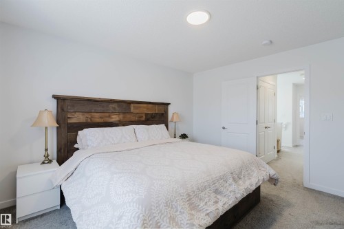 Carpeted bedroom featuring a rustic wood-plank headboard, white walls, and a recessed ceiling light fixture - 5237 Edgemont Boulevard, Edmonton, AB - Indoor Photo Showing Bedroom