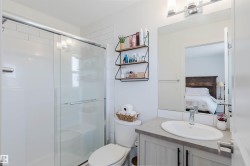 Bathroom featuring a shower with sliding glass doors, white subway tile surround, and a vanity with a countertop sink - 