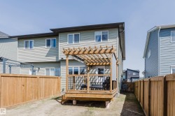 Rear exterior featuring light green siding, a ground-level wood deck with a pergola, and a private wood fence - 
