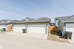 Double garage with white panel doors, light green siding, and a dark shingle roof - 