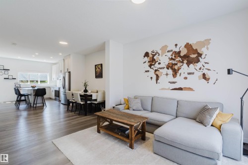 Open-concept living area featuring light wood-finish flooring, recessed lighting, white walls, and a kitchen with white cabinetry and stainless steel appliances - 5237 Edgemont Boulevard, Edmonton, AB - Indoor Photo Showing Living Room