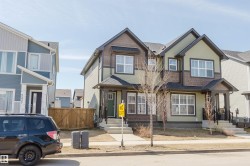 Contemporary duplex featuring a muted green and dark brown exterior with mixed siding, multiple windows, a covered front entry, and a paved walkway - 