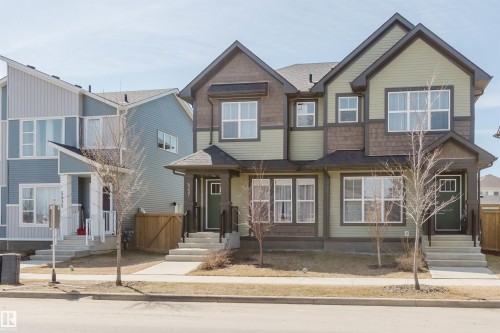 Duplex exterior featuring light green siding, dark brown shake siding accents, multiple white-framed windows, and a covered entry with a dark green door - 5237 Edgemont Boulevard, Edmonton, AB - Outdoor With Facade