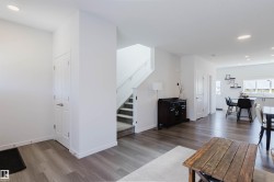 Open-concept interior featuring wood-finish flooring, recessed lighting, and a staircase with carpeted treads - 