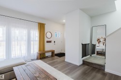 Welcoming entryway featuring a white paneled front door with glass inserts, wood-finish flooring, and bright windows with white trim - 