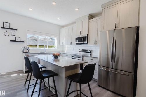 Contemporary kitchen featuring light wood-finish cabinetry, stainless steel appliances, a center island with a light-toned countertop, a white subway tile backsplash, and recessed lighting - 5237 Edgemont Boulevard, Edmonton, AB - Indoor