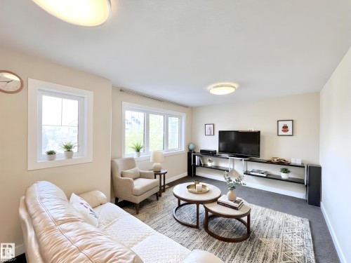 Bright living area featuring light-toned walls, multiple windows with white trim, and two flush-mount ceiling lights - 8967 24 Avenue, Edmonton, AB - Indoor Photo Showing Living Room