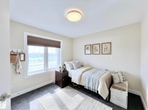 Bright room featuring a large window with pleated blinds, dark carpet flooring, and neutral wall tones - 8967 24 Avenue, Edmonton, AB - Indoor Photo Showing Bedroom