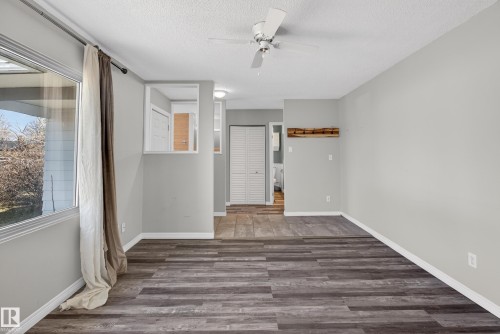 Spacious living area featuring wood-finish flooring, light gray walls, a ceiling fan, and a large window - 5 Linden St, Spruce Grove, AB - Indoor Photo Showing Other Room