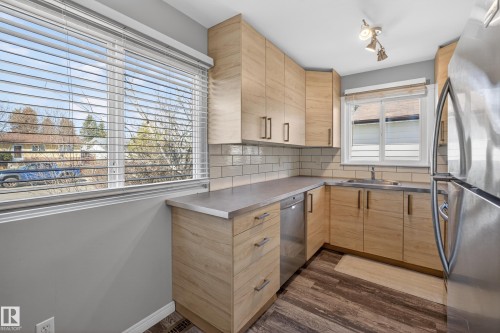 Modern kitchen featuring light wood-finish cabinetry, stainless steel appliances, subway tile backsplash, and wood-finish flooring - 5 Linden St, Spruce Grove, AB - Indoor Photo Showing Kitchen