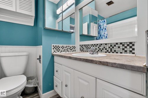 Bathroom vanity with an integrated sink, patterned mosaic tile backsplash, and a large mirror - 5 Linden St, Spruce Grove, AB - Indoor Photo Showing Bathroom
