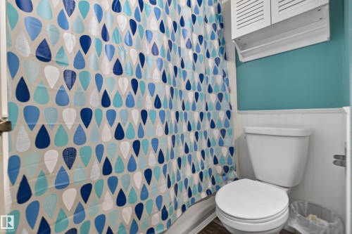Bathroom featuring a white toilet, white wainscoting, and a wall-mounted louvered cabinet - 5 Linden St, Spruce Grove, AB - Indoor Photo Showing Bathroom