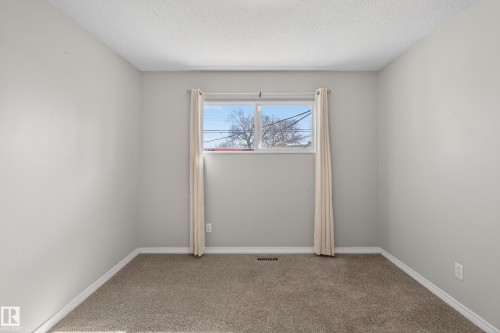Neutral-toned room featuring a single window with drapes, textured ceiling, and plush carpet flooring - 5 Linden St, Spruce Grove, AB - Indoor Photo Showing Other Room