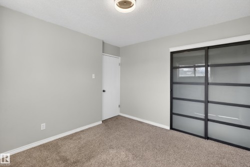 Room with neutral gray wall paint, textured carpet flooring, and a flush mount ceiling light fixture - 5 Linden St, Spruce Grove, AB - Indoor Photo Showing Other Room