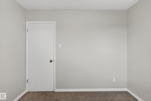 Gray wall paint with white trim, a closed white door with a black knob, and brown carpet flooring - 5 Linden St, Spruce Grove, AB - Indoor Photo Showing Other Room
