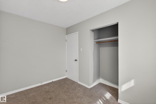 Interior room featuring light gray wall paint, textured ceiling, brown carpet flooring, white baseboards, and a recessed ceiling light fixture - 5 Linden St, Spruce Grove, AB - Indoor Photo Showing Other Room