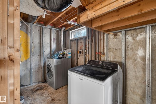 Utility space featuring exposed wood joists, concrete walls with metal framing, a small window, and visible ductwork - 5 Linden St, Spruce Grove, AB - Indoor Photo Showing Laundry Room