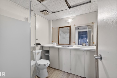 Restroom featuring a drop ceiling, white walls, and a wood-finish floor - 5 Linden St, Spruce Grove, AB - Indoor Photo Showing Bathroom