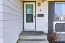 Entryway featuring white horizontal siding, a storm door, a wall-mounted light fixture, and concrete steps - 5 Linden St, Spruce Grove, AB  - Outdoor With Exterior 