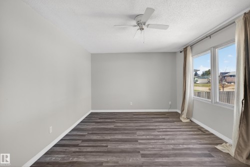 Spacious room featuring wood-finish flooring, light grey walls, and a white ceiling fan - 5 Linden St, Spruce Grove, AB - Indoor Photo Showing Other Room