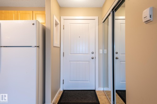 Entryway featuring a white paneled door, mirrored closet doors, and tile flooring - #314 240 Spruce Ridge Rd, Spruce Grove, AB - Indoor