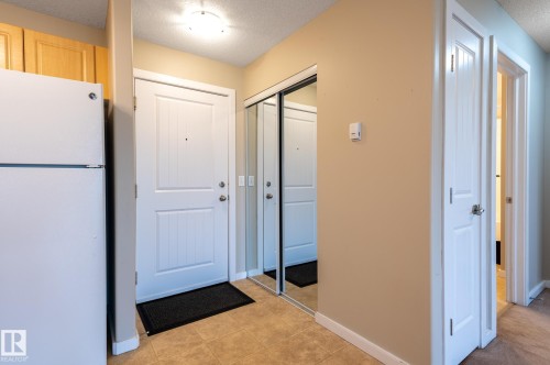 Entryway featuring a panel door, tiled flooring, and a mirrored closet - #314 240 Spruce Ridge Rd, Spruce Grove, AB - Indoor Photo Showing Other Room