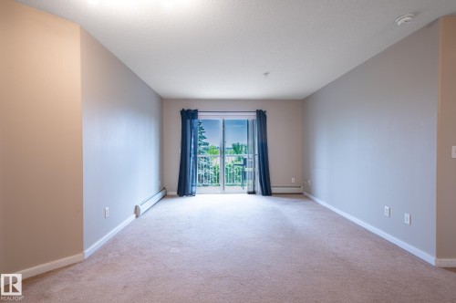Spacious interior featuring neutral wall tones, plush carpet flooring, and white trim - #314 240 Spruce Ridge Rd, Spruce Grove, AB - Indoor Photo Showing Other Room