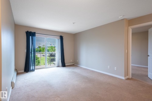 Spacious room with neutral-toned carpet, light beige walls, and white trim - #314 240 Spruce Ridge Rd, Spruce Grove, AB - Indoor Photo Showing Other Room