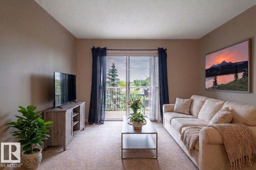 Living area featuring a sliding glass door opening to a private balcony with metal railings - #314 240 Spruce Ridge Rd, Spruce Grove, AB - Indoor Photo Showing Living Room