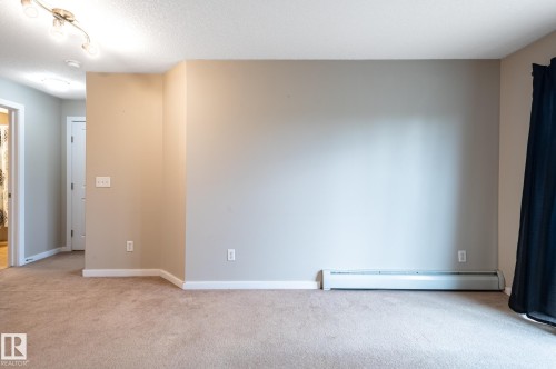 Carpeted room with a baseboard heating unit, neutral wall paint, and white trim - #314 240 Spruce Ridge Rd, Spruce Grove, AB - Indoor Photo Showing Other Room