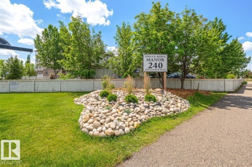 Landscaping featuring a rock garden, green shrubs, and mature trees - #314 240 Spruce Ridge Rd, Spruce Grove, AB - Outdoor With Backyard