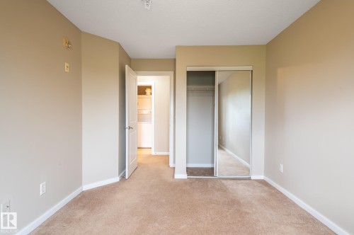 Carpeted room featuring a mirrored sliding closet door, neutral wall paint, and white trim - #314 240 Spruce Ridge Rd, Spruce Grove, AB - Indoor Photo Showing Other Room