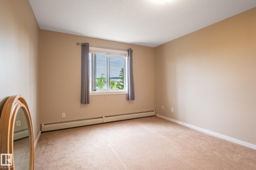 Carpeted room featuring neutral wall paint, a window with exterior scenery, a white ceiling with a flush-mount light fixture, and white baseboard trim - #314 240 Spruce Ridge Rd, Spruce Grove, AB - Indoor Photo Showing Other Room