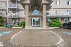 Building entrance featuring a covered portico with brick-patterned columns and a glass double-door entry - 