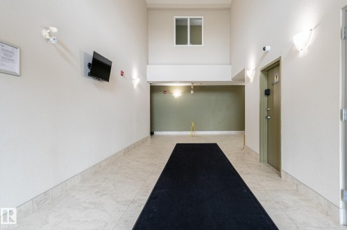 Spacious hall with light-toned tile flooring, tall ceilings, and contemporary wall sconces - #314 240 Spruce Ridge Rd, Spruce Grove, AB - Indoor Photo Showing Other Room