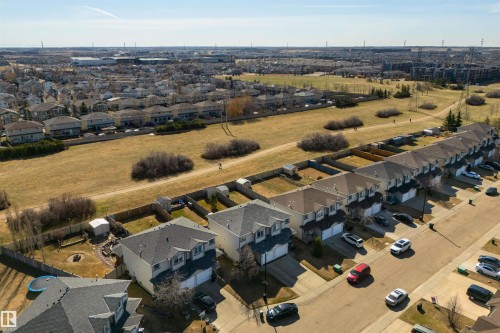 Aerial perspective showcasing a residential street with multiple detached homes and townhomes, each featuring paved driveways and individual garages - 2923 30 Street, Edmonton, AB - Outdoor With View