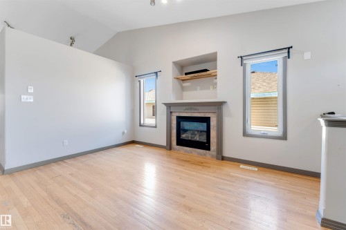 Living area featuring a gas fireplace with a tiled surround, a decorative mantel, and built-in shelving - 4812 148 Avenue, Edmonton, AB - Indoor Photo Showing Living Room With Fireplace