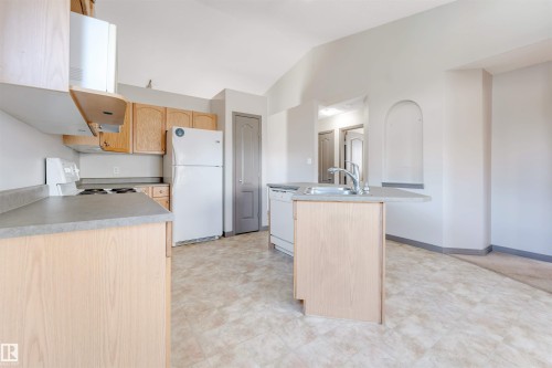 Kitchen featuring light wood-finish cabinetry, a built-in electric range, and a dual-basin sink with a chrome faucet - 4812 148 Avenue, Edmonton, AB - Indoor Photo Showing Kitchen