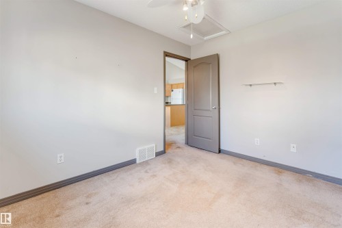 Carpeted room with light gray walls, dark trim, a ceiling fan, and a gray interior door - 4812 148 Avenue, Edmonton, AB - Indoor Photo Showing Other Room