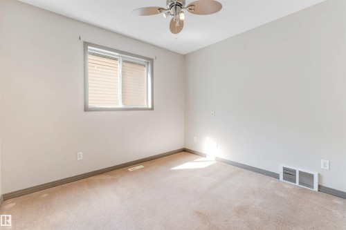 Carpeted interior with light-toned walls and a window featuring horizontal blinds - 4812 148 Avenue, Edmonton, AB - Indoor Photo Showing Other Room