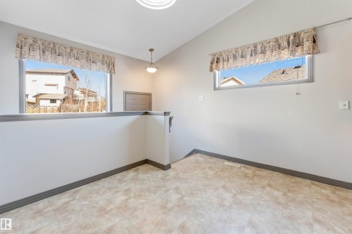 Open concept room featuring two windows, neutral tone walls, and pattern flooring - 4812 148 Avenue, Edmonton, AB - Indoor Photo Showing Other Room