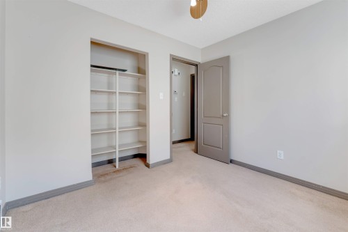Carpeted room with a built-in shelving unit, a paneled interior door, and ceiling fan - 4812 148 Avenue, Edmonton, AB - Indoor Photo Showing Other Room