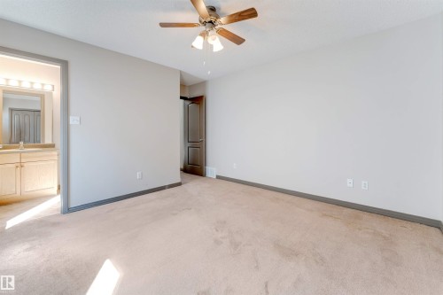 Carpeted room with a ceiling fan light fixture, light gray walls, and dark trim - 4812 148 Avenue, Edmonton, AB - Indoor Photo Showing Other Room