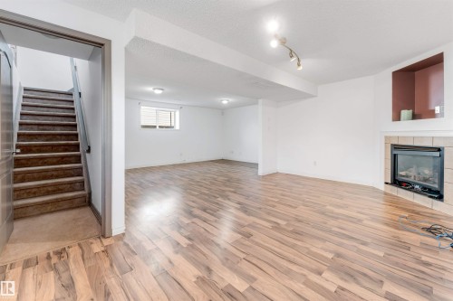 Spacious room featuring wood-finish flooring and a corner fireplace with tile surround - 4812 148 Avenue, Edmonton, AB - Indoor With Fireplace
