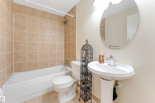 Bathroom featuring a pedestal sink, oval frameless mirror, chrome faucet, and a tiled shower/tub combination - 4812 148 Avenue, Edmonton, AB - Indoor Photo Showing Bathroom