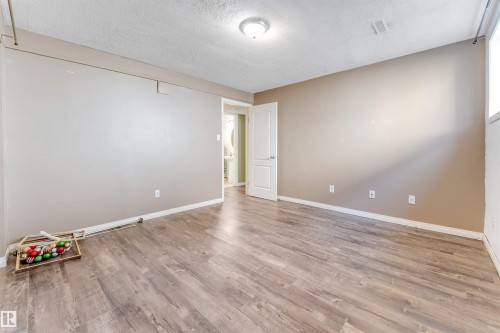 Spacious room featuring wood-finish flooring, neutral-toned walls, and a recessed light fixture - 4812 148 Avenue, Edmonton, AB - Indoor Photo Showing Other Room