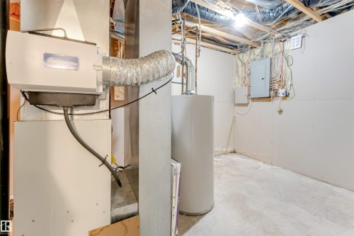Basement utility area featuring a hot water heater, exposed ceiling joists, and concrete flooring - 4812 148 Avenue, Edmonton, AB - Indoor Photo Showing Basement