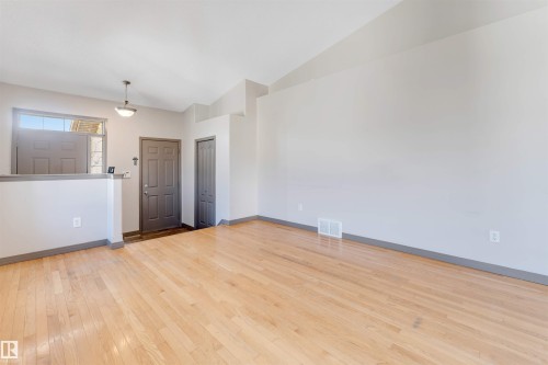 Open concept living area featuring light wood-finish flooring, vaulted ceilings, and a neutral wall palette - 4812 148 Avenue, Edmonton, AB - Indoor Photo Showing Other Room