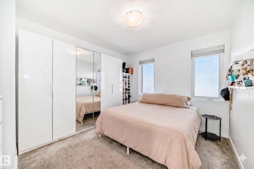 White walls framing two windows with roller shades, accompanied by light gray carpeting - 14812 98 Avenue, Edmonton, AB - Indoor Photo Showing Bedroom